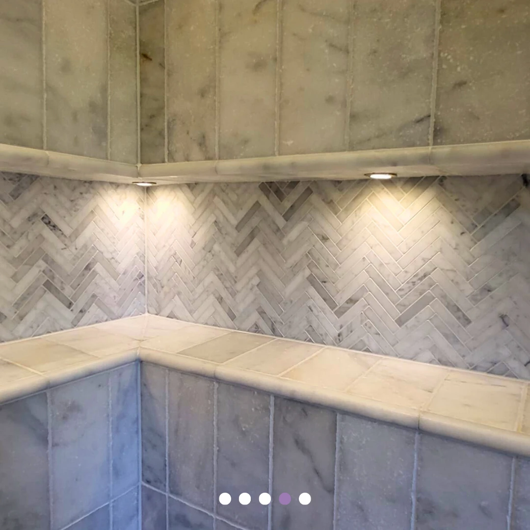 Sense Renovations carousel detail of an illuminated herringbone-tiled shower niche